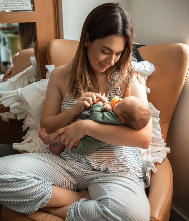 A woman holding her baby in the arms of another person.