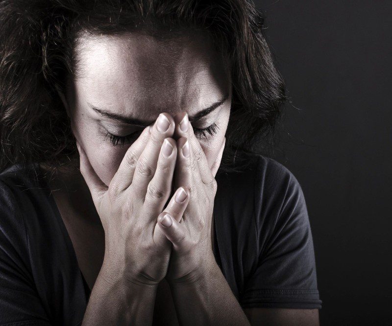 A woman with her hands over her face.