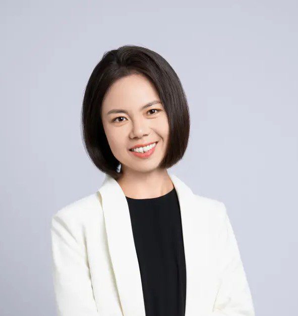 A woman in white jacket smiling for the camera.